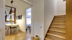 A hallway with a wooden floor, a dining area with a table and chairs, and a staircase. - Malenchini 6 in Firenze (Florence)