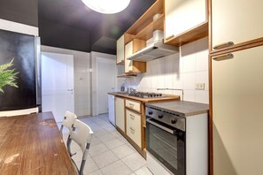 Una cocina compacta con estufa, horno y gabinetes blancos.