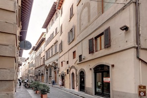 A narrow street lined with historic buildings, featuring arched doorways and traditional shutters. - Parione 12 in Firenze (Florence)