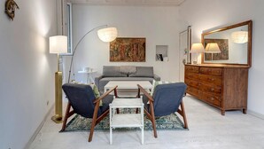 A modern living room with a sofa, two armchairs, a coffee table, a floor lamp, a dresser, and a large mirror.