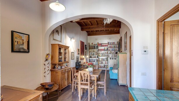 Una habitación acogedora con una mesa de comedor de madera, sillas, una estantería y una cama con colchón azul.