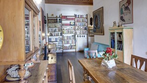 Una habitación acogedora con una mesa de comedor de madera, una estantería llena de libros y una lámpara antigua.