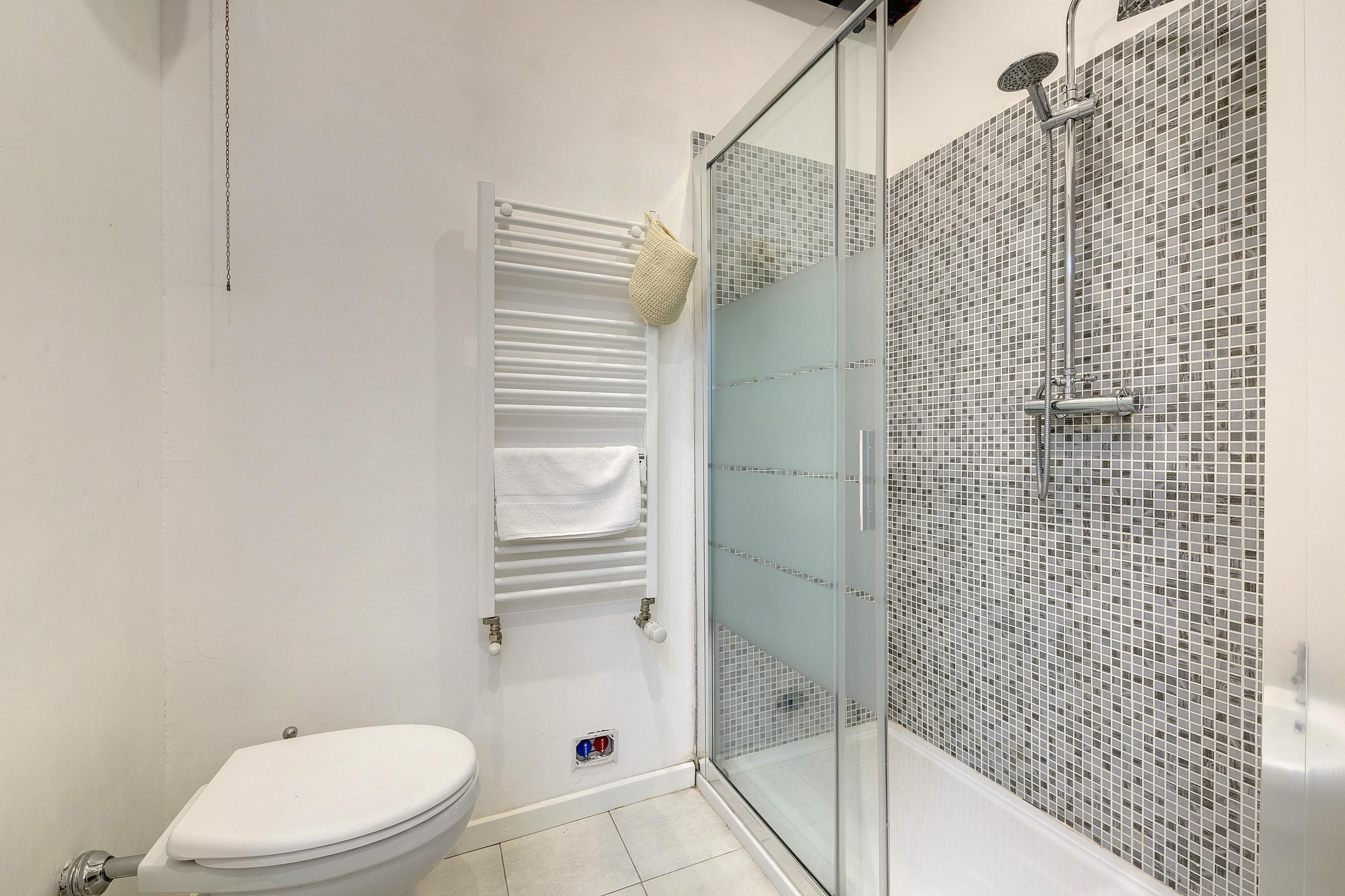 Ein Badezimmer mit Toilette, einer Duschkabine und einem Handtuchhalter.