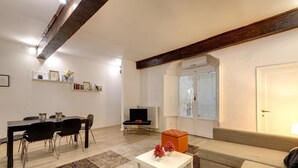 A modern living room with a dining area, a sofa, a coffee table, and a TV.