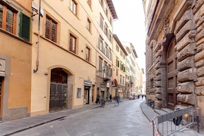 A narrow street lined with historic buildings, featuring a mix of stone and plaster facades, and a few bicycles parked along the sidewalk.