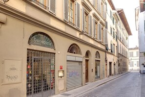 A street view with a building labeled "benedicta" featuring a closed shutter, a metal gate, and a sign indicating "servizio" and "fiaschetteria" services. - Benedetta 8 in Firenze (Florence)