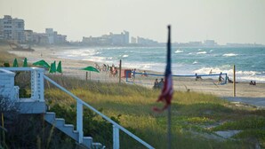 Una playa con una red de voleibol, sombrillas y una bandera.