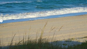 Una playa arenosa con olas acercándose a la orilla.