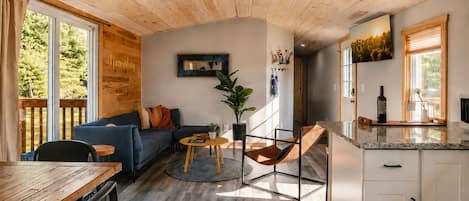 A modern interior with a wooden ceiling, a sofa, a dining table, and a kitchen area.