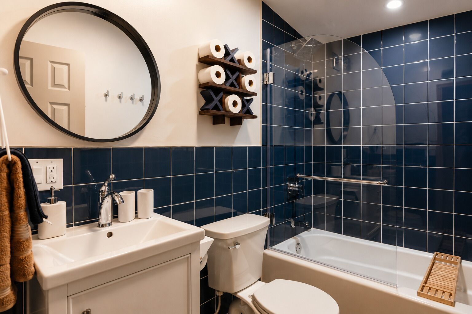 Un baño moderno con un espejo redondo, un inodoro, un lavamanos y una bañera.