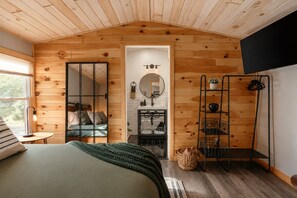 Een gezellige slaapkamer met een bed, een spiegel, een dressoir en een televisie.