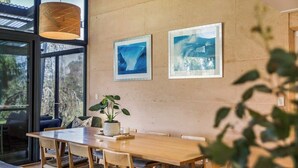 Ein Essbereich mit einem Holztisch und Stühlen, einer Zimmerpflanze und gerahmten Bildern an der Wand.