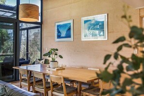 A dining area with a wooden table and chairs, a potted plant, and framed pictures on the wall.