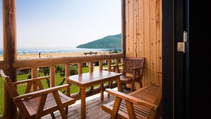 Une terrasse en bois avec des tables et des chaises donnant sur une plage.