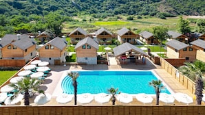 Un complexe hôtelier comprenant plusieurs chalets en bois, une piscine centrale et des espaces de détente en plein air.