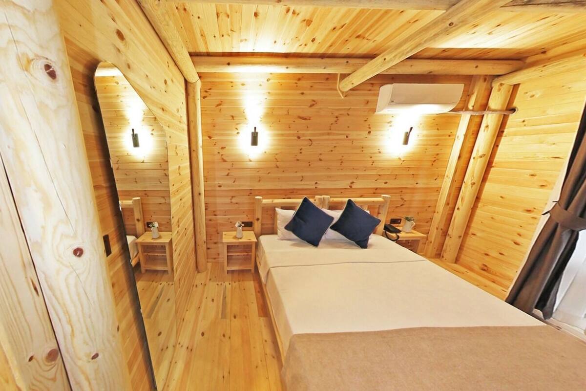 Ein Holzhütten-Zimmer mit einem Bett, zwei Nachttischen und Wandleuchten.