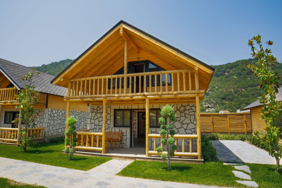 Eine Holzhütte mit einer Steinfassade, einem Balkon und einem gepflasterten Weg zum Eingang.