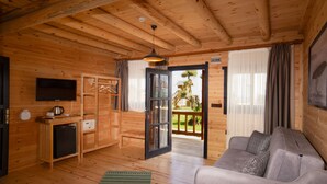 Une cabane en bois comprenant un espace de vie, une kitchenette et un balcon avec vue sur l’extérieur.