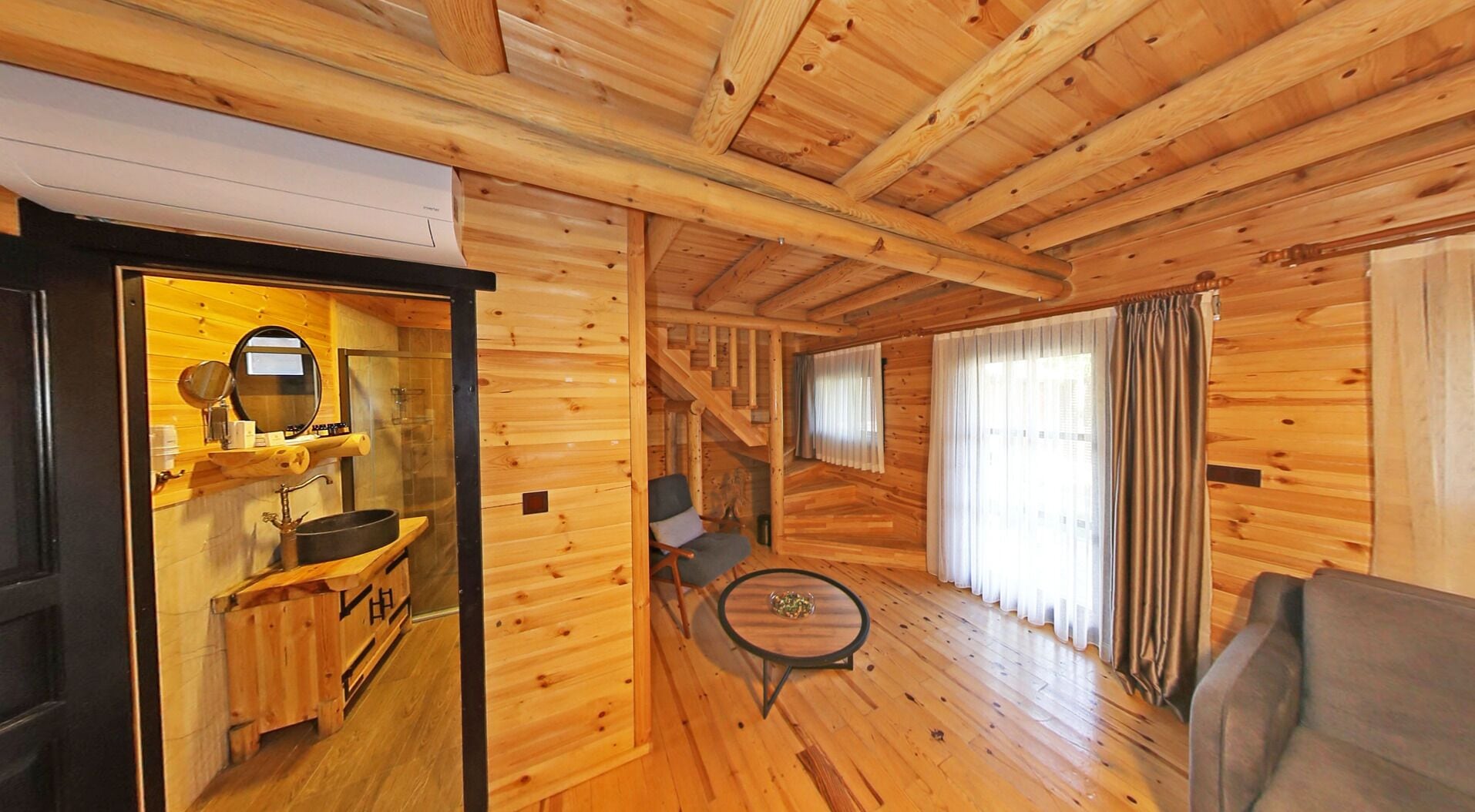 A wooden cabin interior with a kitchen, a dining area, and a living room.