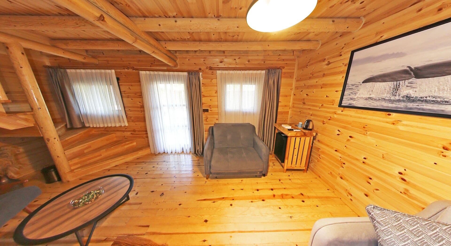 A wooden cabin interior with a sofa, a table, and a chair.