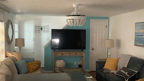 Una sala de estar con televisor, sofá y armarios.