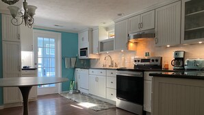 Una cocina moderna con armarios blancos, electrodomésticos de acero inoxidable y un comedor con mesa y sillas.