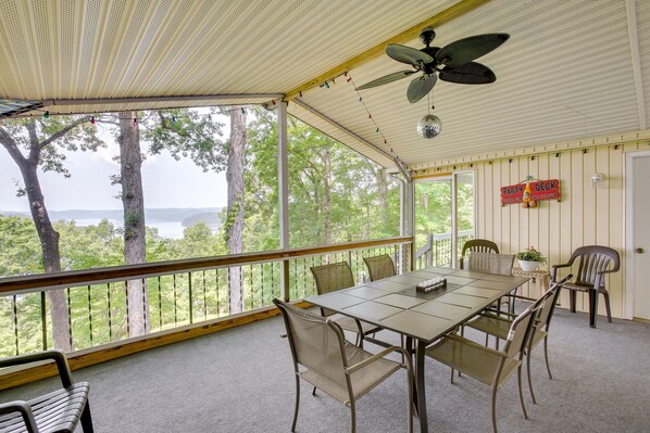 A covered outdoor area with a table and chairs, a ceiling fan, and a view of trees and water. - Bright Byrdstown Home w/ Views of Dale Hollow Lake (Byrdstown)