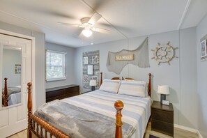 A bedroom with a bed, a nightstand, a ceiling fan, a window, and wall decorations including a 'No Wake' sign and a ship's wheel. - Bright Byrdstown Home w/ Views of Dale Hollow Lake (Byrdstown)