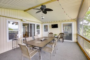A covered outdoor dining area with a table, chairs, a ceiling fan, and a TV screen. - Bright Byrdstown Home w/ Views of Dale Hollow Lake (Byrdstown)