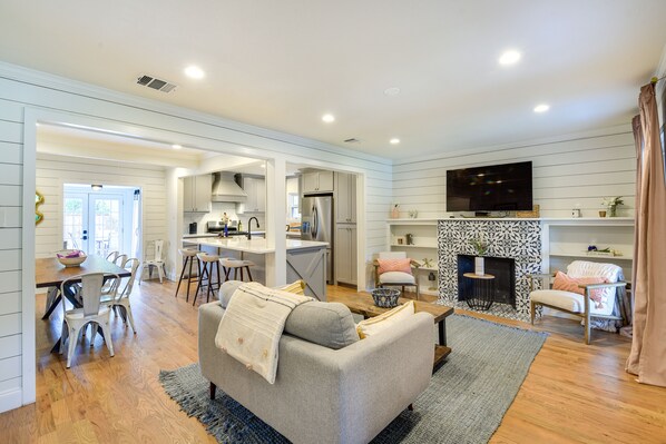 A spacious living room with a grey sofa, wooden dining table, and a fireplace. - ‘Pecan Blue’ Frisco Hub: Dtwn, Dining & Stadiums! (Frisco)