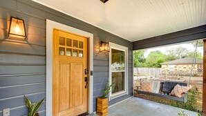 A wooden front door with a glass panel, a porch with a swing seat, and two potted plants. - ‘Pecan Blue’ Frisco Hub: Dtwn, Dining & Stadiums! (Frisco)
