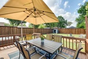 A deck with a table and chairs, a large umbrella, and a wooden fence. - ‘Pecan Blue’ Frisco Hub: Dtwn, Dining & Stadiums! (Frisco)