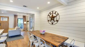 A dining area with a wooden table, white chairs, and a Texas state star wall decoration. - ‘Pecan Blue’ Frisco Hub: Dtwn, Dining & Stadiums! (Frisco)