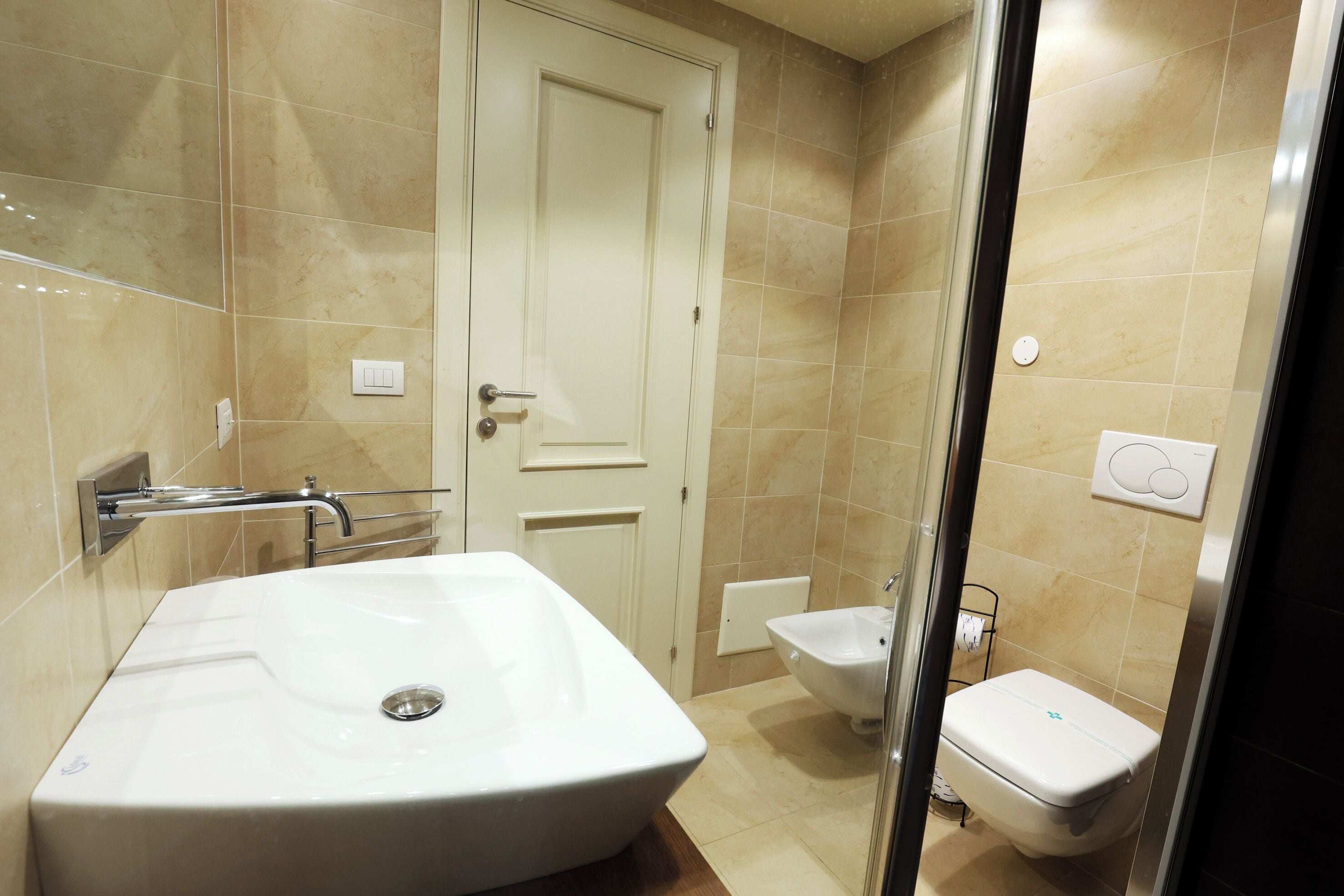 Ein Badezimmer mit einem großen, rechteckigen Waschbecken, einer Toilette und einem Bidet.