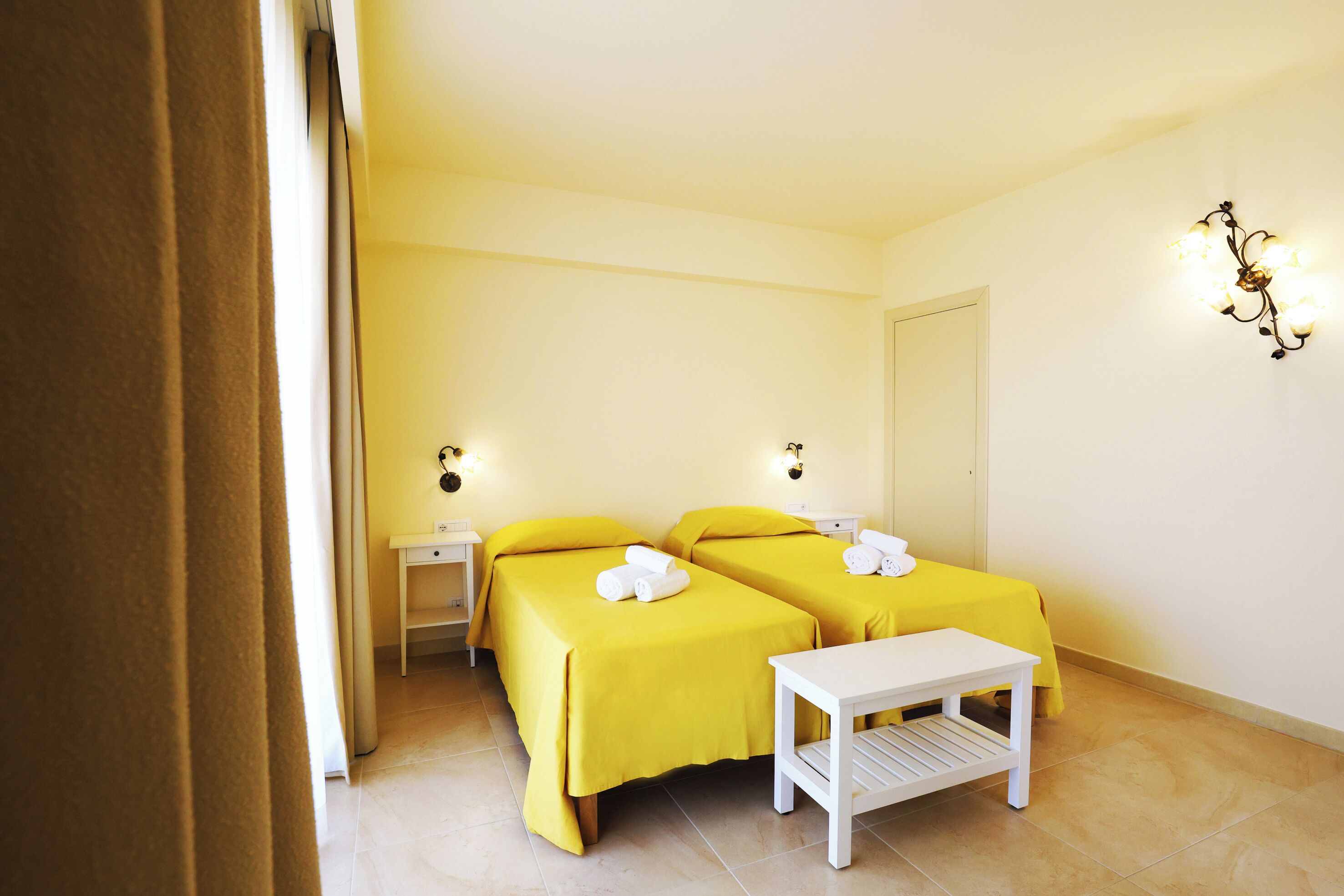 A hotel room with two beds, a small table, and a nightstand.