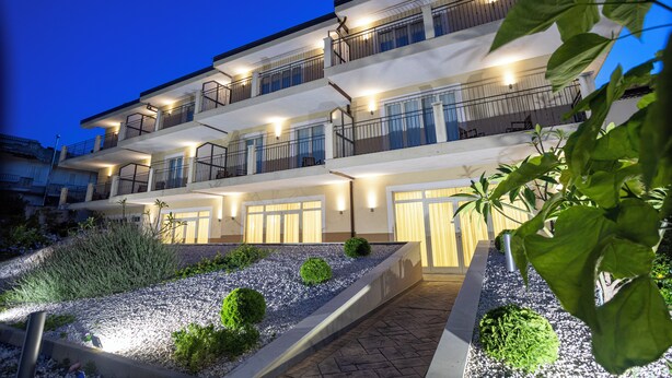 A multi-story hotel with balconies and a landscaped garden area. - Verdello Home Savoca (Savoca)