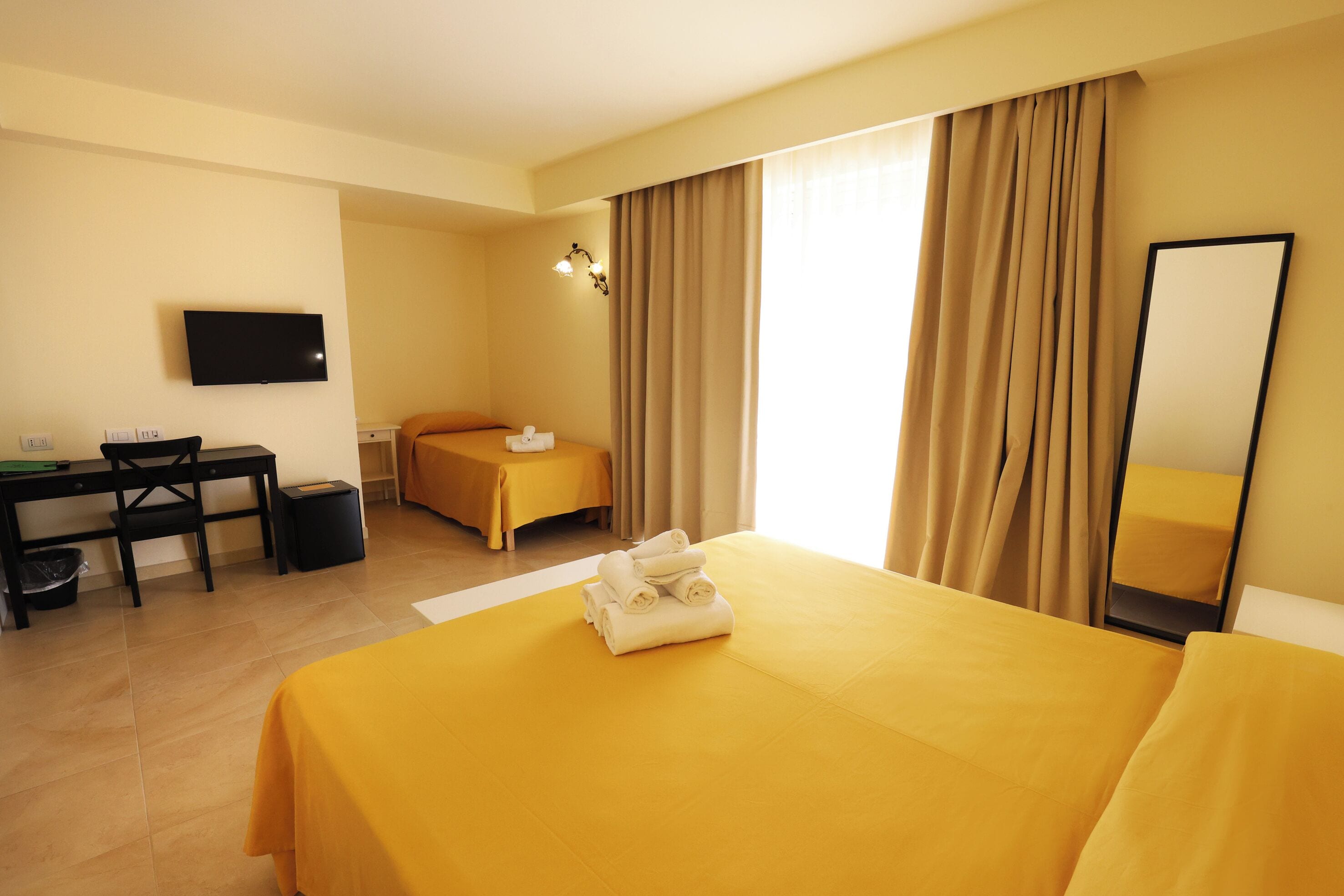 Ein Hotelzimmer mit Bett, Schreibtisch, Stuhl, Fernseher und Bad.