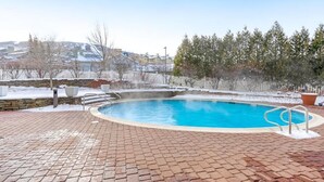A swimming pool with a brick deck, surrounded by a fence and trees. - 5 minute walk to lifts and Stratton Village! Cozy fireplace with a private patio (Stratton)
