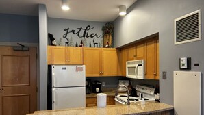A kitchen with wooden cabinets, a white refrigerator, a microwave, and a gas stove. - 5 minute walk to lifts and Stratton Village! Cozy fireplace with a private patio (Stratton)