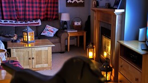 A cozy living room with a fireplace, wooden furniture, and decorative lanterns. - 5 minute walk to lifts and Stratton Village! Cozy fireplace with a private patio (Stratton)