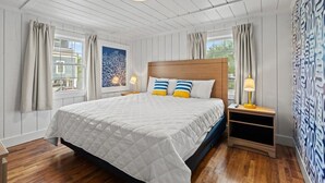 A bedroom with a large bed, wooden headboard, two bedside tables, and a window with curtains.