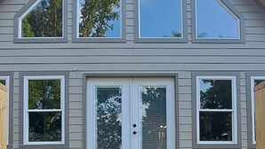 Una casa de dos pisos con un amplio balcón, una puerta principal con panel de vidrio y varias ventanas.