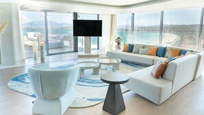 A modern living room with a large sofa, a coffee table, and a TV. - Swissôtel Resort And Spa Cesme (Cesme)