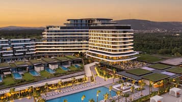 A modern hotel with multiple floors, a swimming pool, and outdoor seating areas.