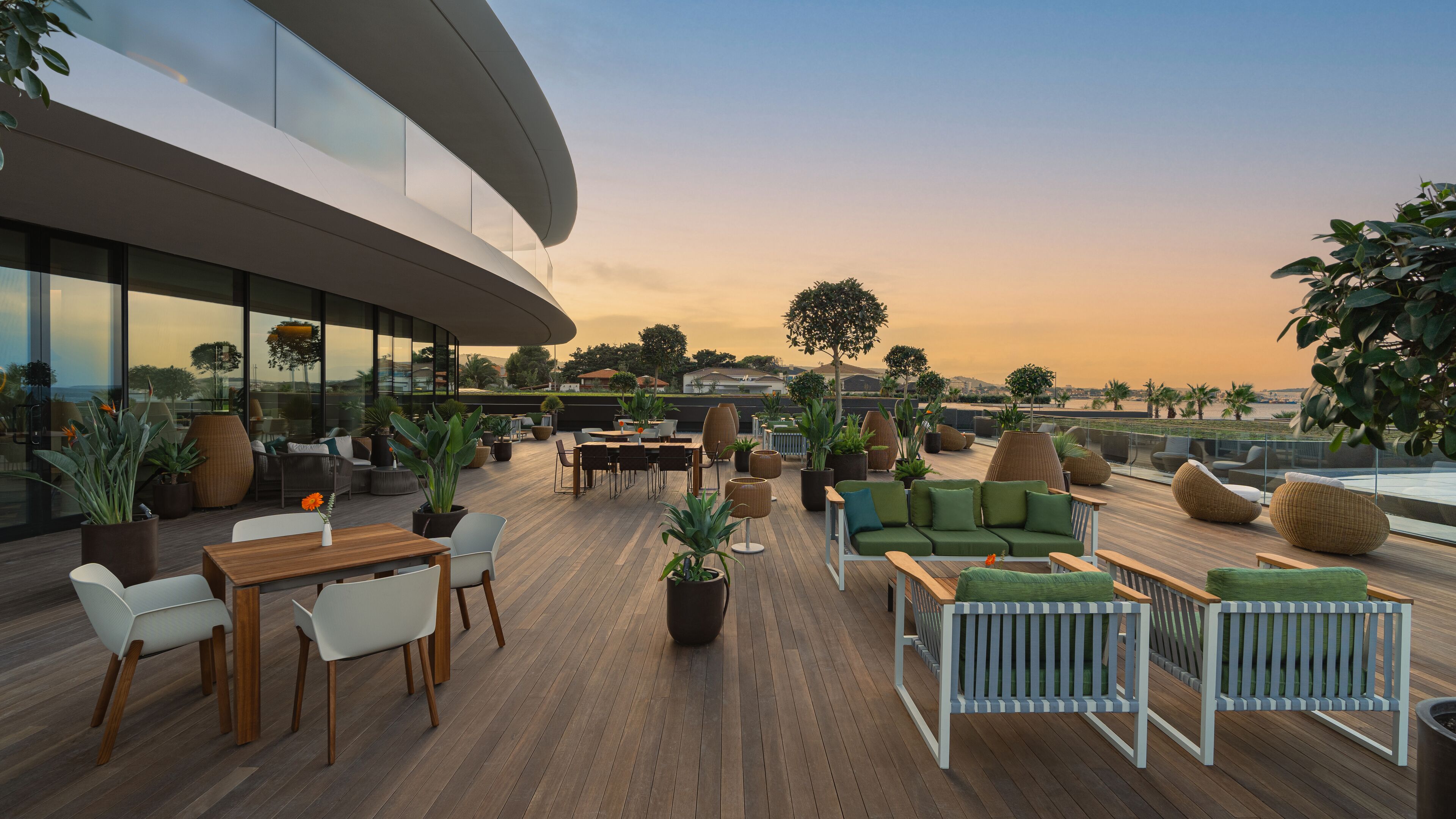 Una terraza en la azotea con suelo de madera, mobiliario exterior y plantas en macetas.