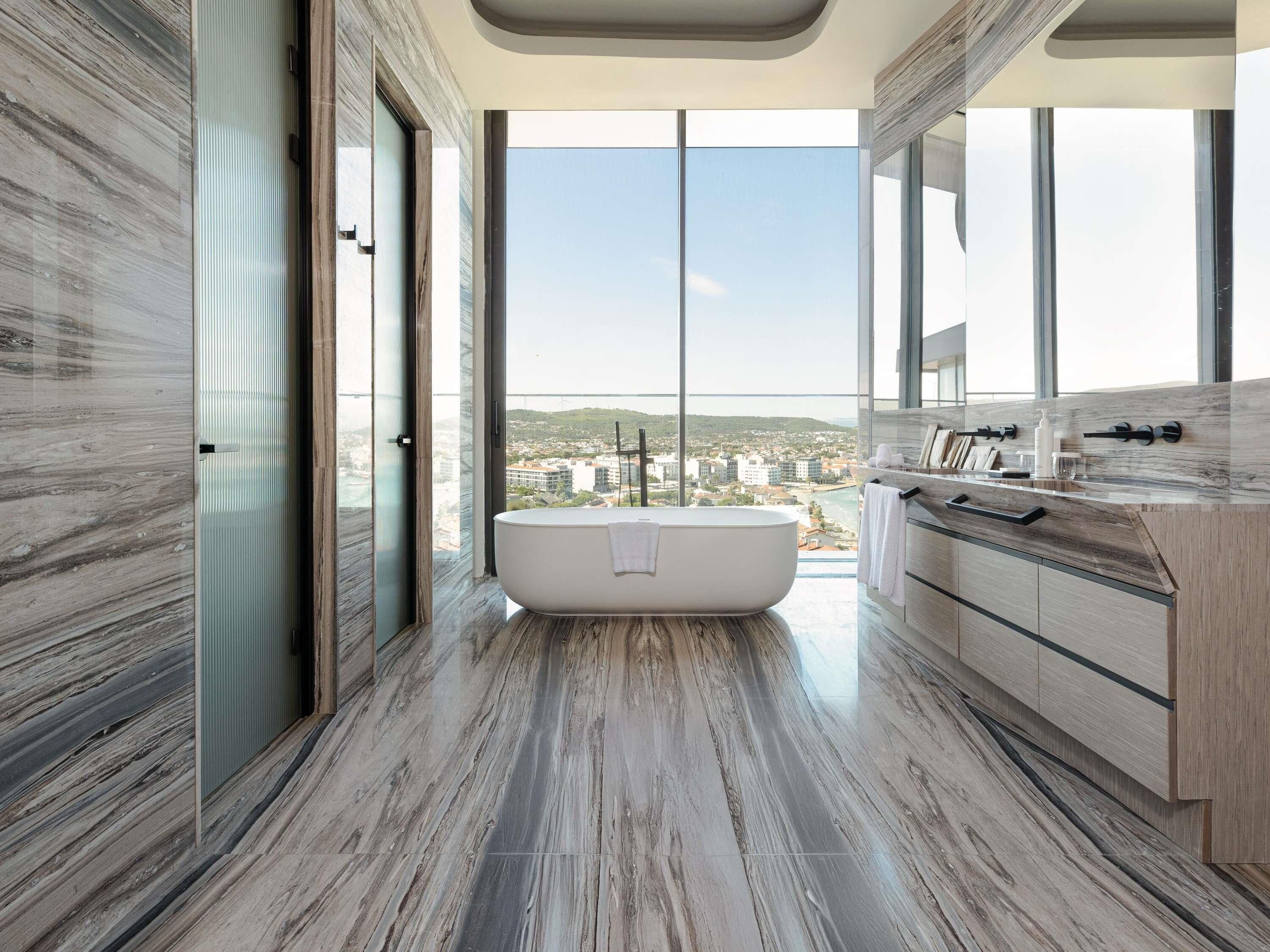 A modern bathroom with a freestanding bathtub, large windows, and a city view.