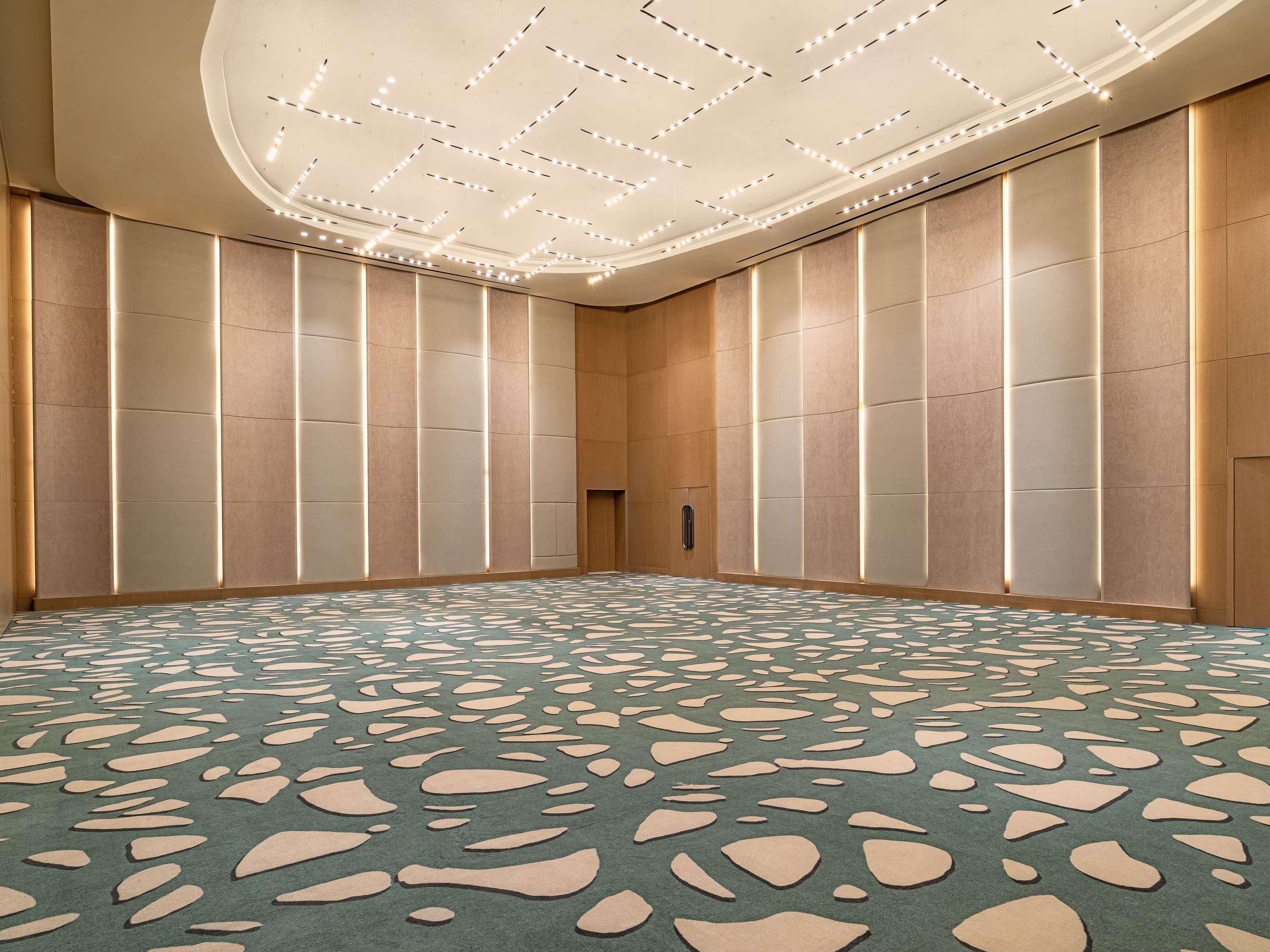 A conference room with a patterned carpet, recessed lighting, and a modern ceiling design.