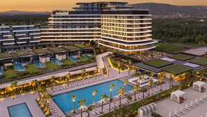 A modern hotel with multiple floors, a swimming pool, and outdoor seating areas. - Swissôtel Resort And Spa Cesme (Cesme)