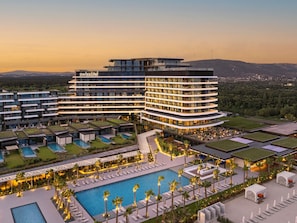 Un hôtel moderne à plusieurs étages, doté d’une piscine et d’espaces extérieurs aménagés pour se détendre.