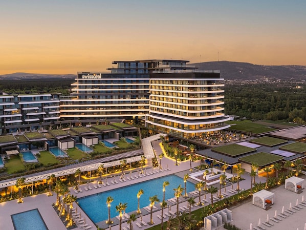 A modern hotel with multiple floors, a swimming pool, and outdoor seating areas.